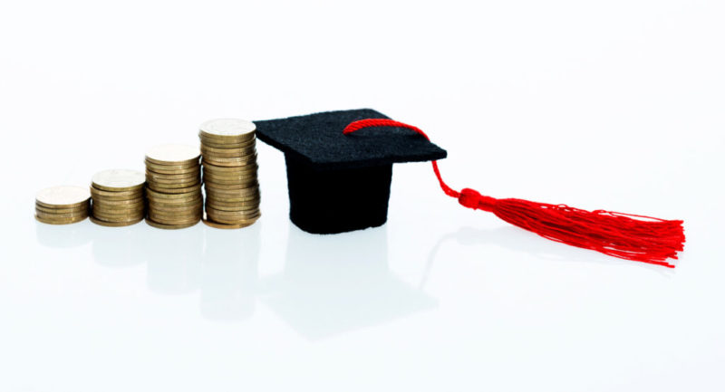 Graduation hat and heap of coins Graduation hat and heap of coins